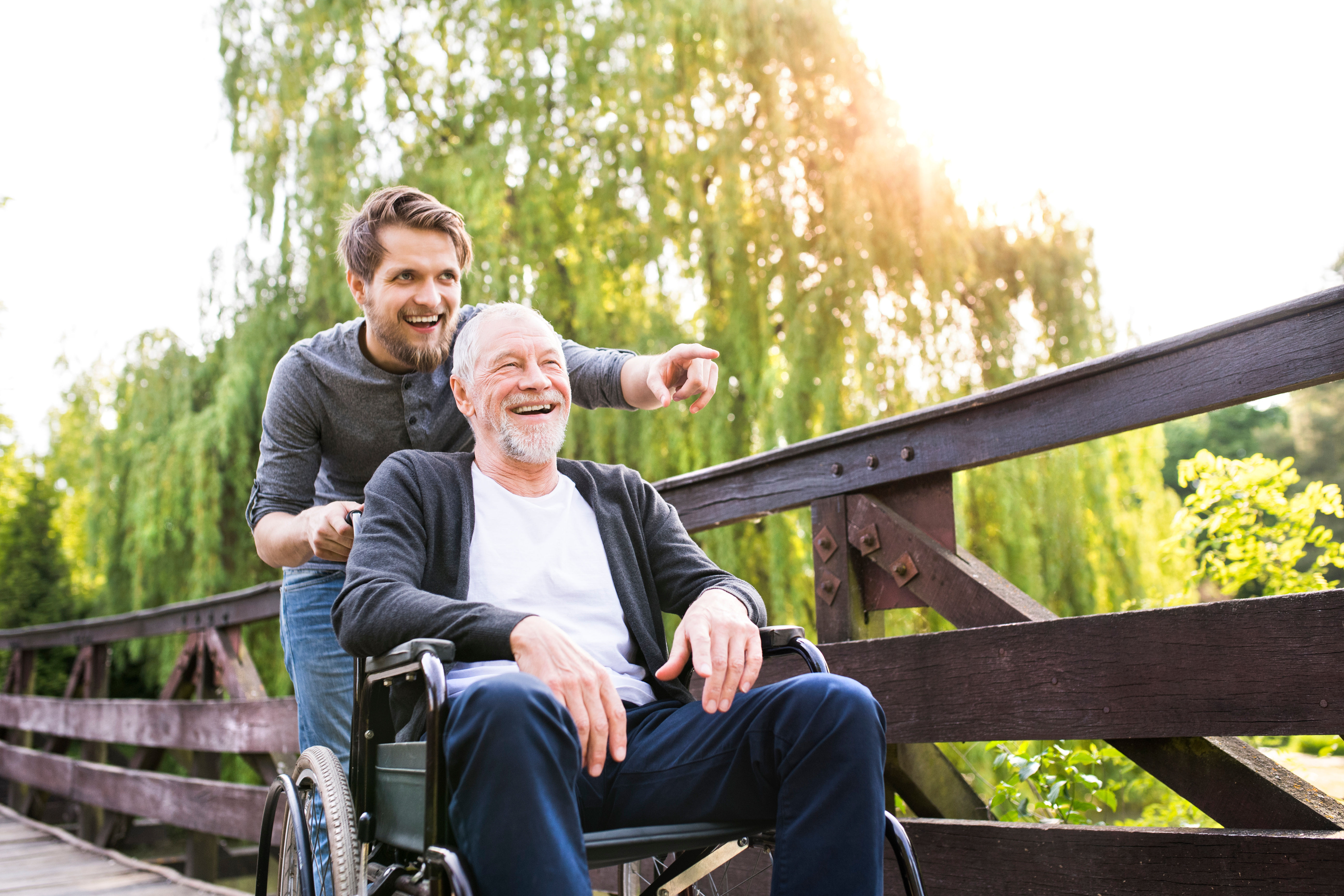 Zwei Männer auf einer Brücke im Grünen, Rollstuhlfahrt – ORTHOPARTNER Medizintechnik Porta